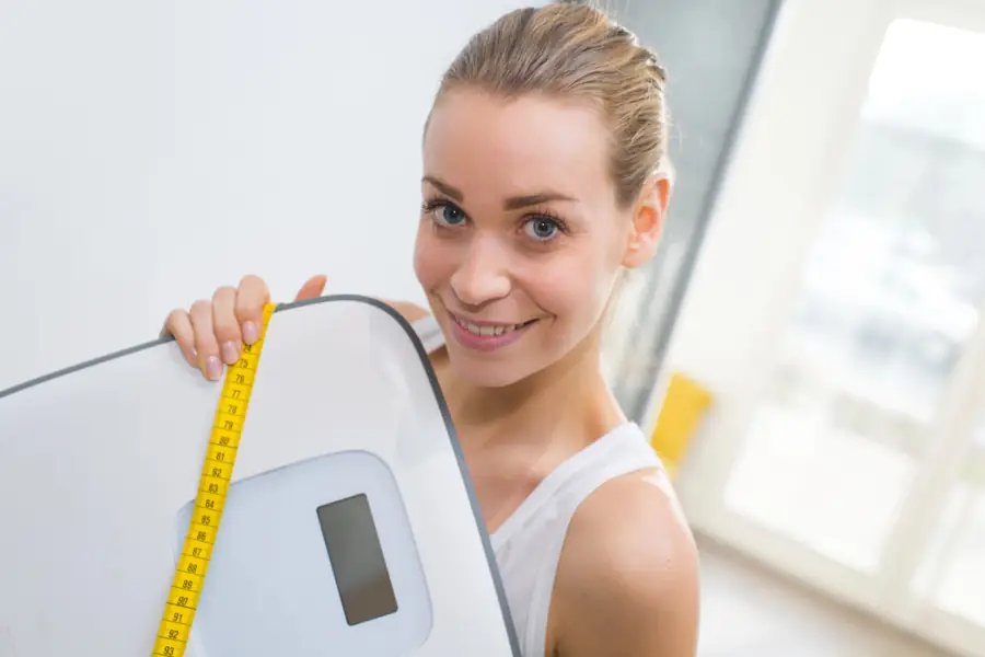 Woman Holding Weight Scale Tape Measurer Smiling woman with scale and measuring tape.